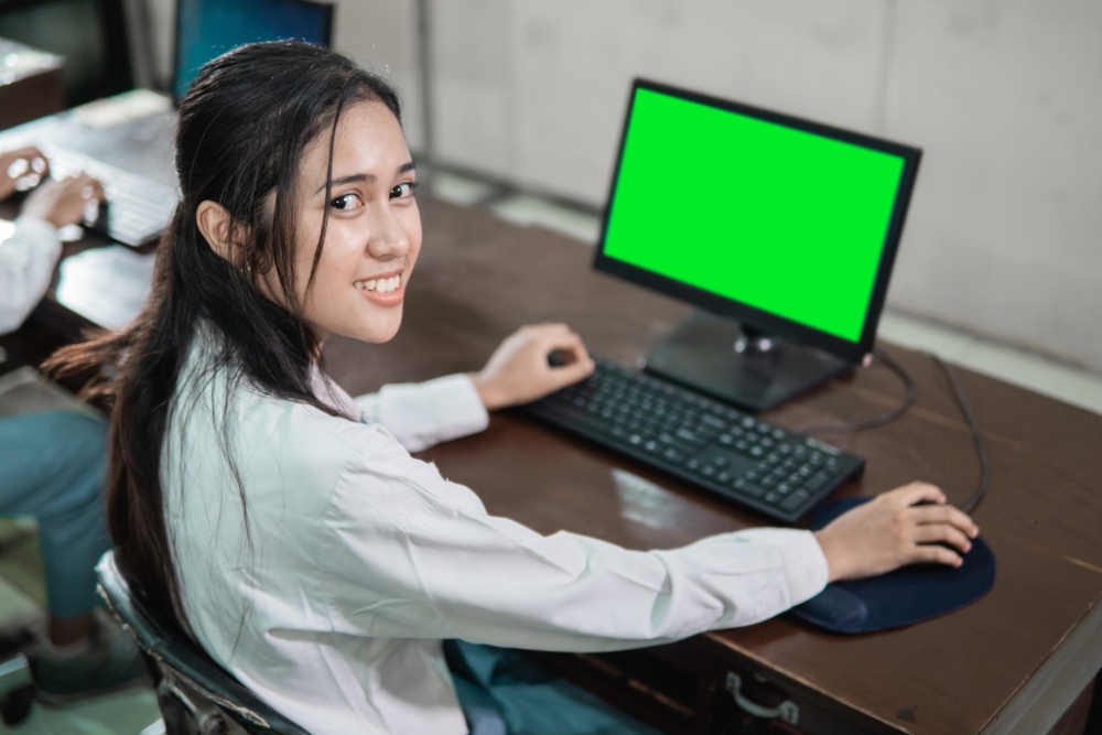 close up of a female student smiling with a look back while using a computer